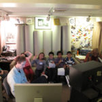 Engineer Tom Stiles and Judith Roche sitting in a recording studio's control room with a group of students.