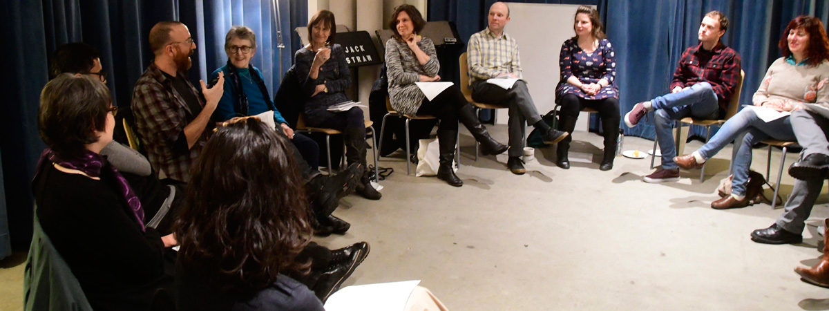 Jack Straw Writers, curator, and staff sitting on chairs in a large circle in the studio at Jack Straw Cultural Center.