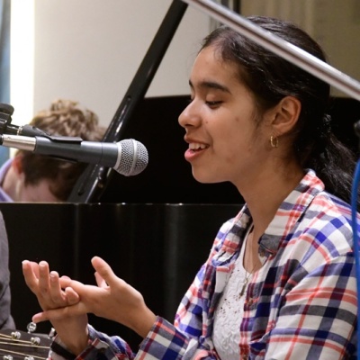 A visually impaired girl is recording vocals in front of a microphone