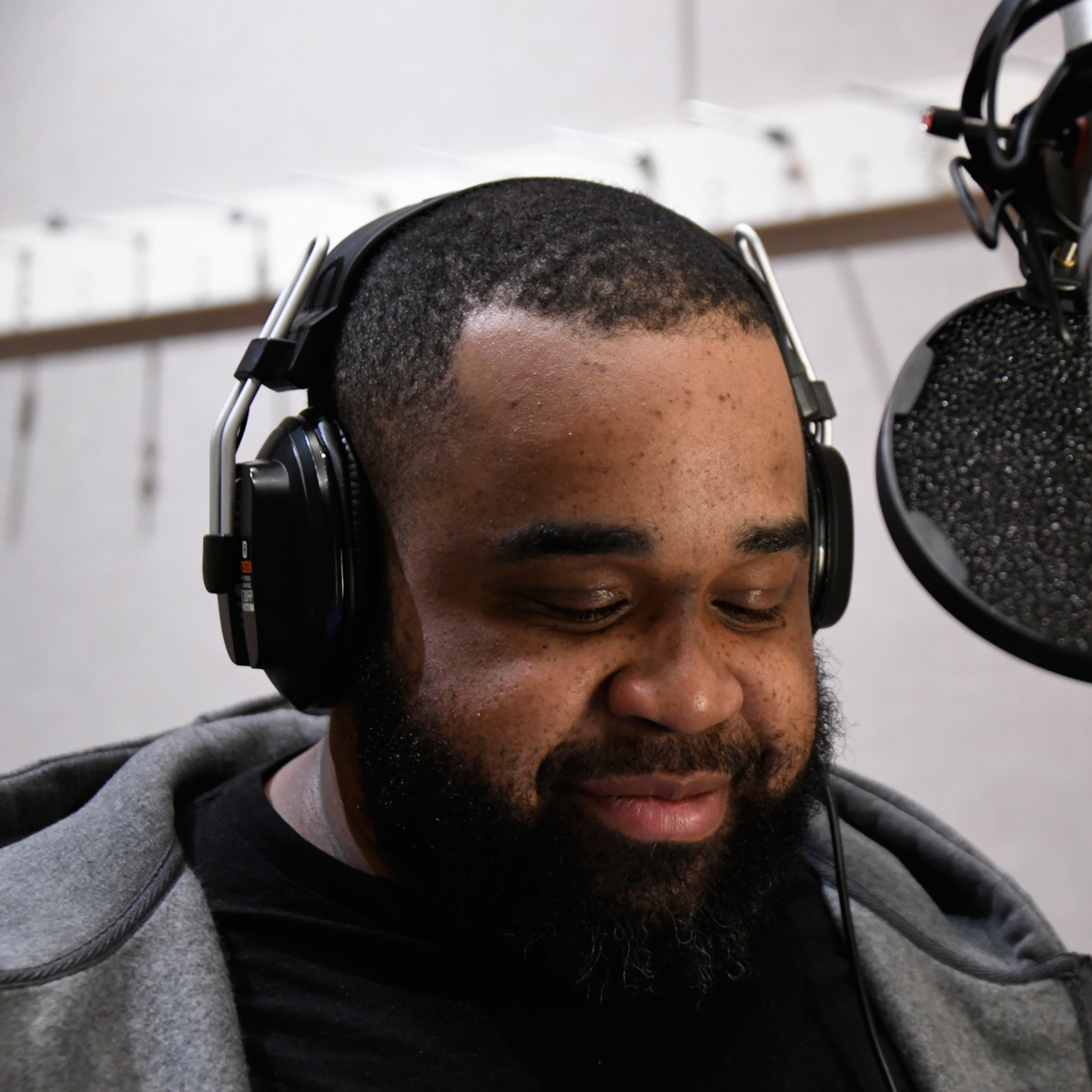 Jeffrey Lee Cheatham II wearing headphones, looking down, with a microphone pop screen to the right