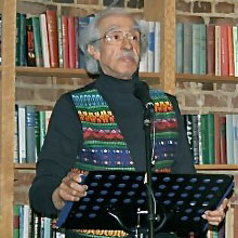 Jose Carrillo standing in front of bookshelves, a music stand facing him.