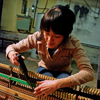 Tiffany Lin uses a soldering iron on the insides of a piano