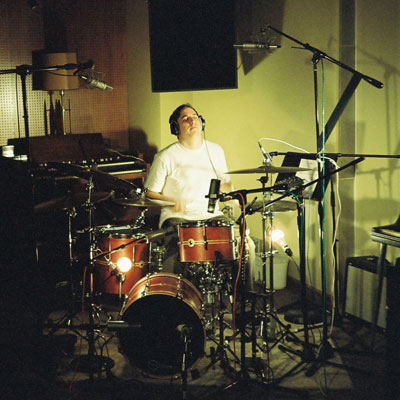Murphy Janssen sitting at a drum kit with mics on stands around it.