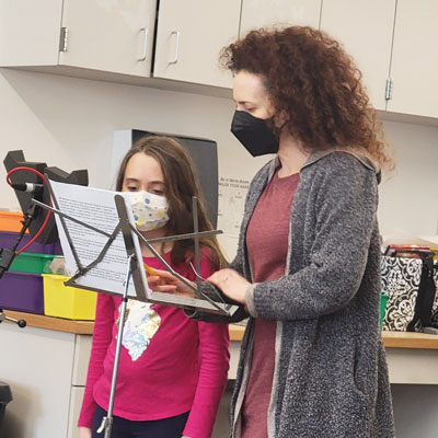 Daniel Bagley student and vocal coach Meg McLynn stand at a music stand with a piece of paper on it