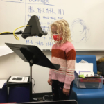 A student standing at a microphone, looking down at a music stand