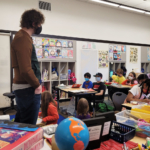 Gavin Reub standing in a classroom, Daniel Bagley students sitting at desks