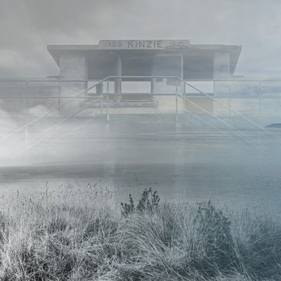 Image of an abandoned fort with the words 1909 KINZIE at the top, shrouded in fog, grass in the foreground