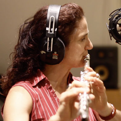 Jessica Lurie in profile, playing flute and wearing headphones