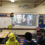 Students watch Sunam Ellis and Brenda Arellano make strange faces on a projection screen.