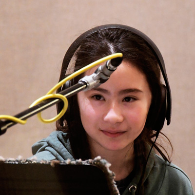 A student wearing headphones at a microphone.