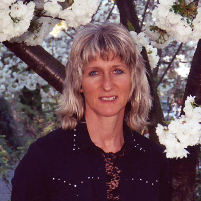 Photo of Kathryn Christman standing in front of a flowering tree.