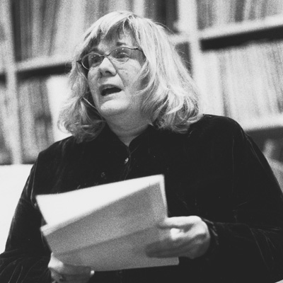 Black and white photo of Rebecca Loudon, holding pages and speaking.