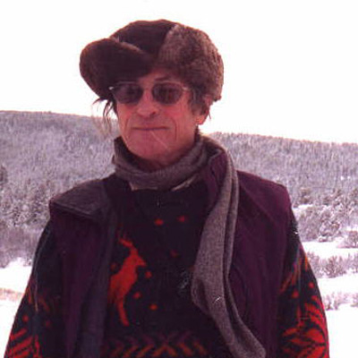 Photo of Richard Denner wearing sunglasses and a winter hat and coat, with a snowy landscape behind him.