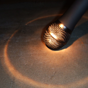 A microphone rests on the floor, with a circle of reflected light around it.