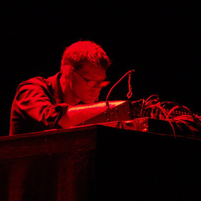 Joe Colley, illuminated with red, controlling a sound mixing board.