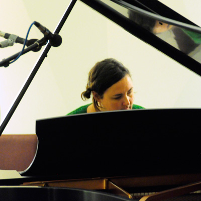 Melanie Noel playing piano, two microphones above her and to the left.