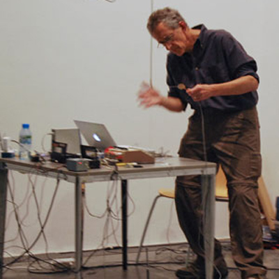 Richard Lerman standing at a table with a computer and other electronic equipment on it.