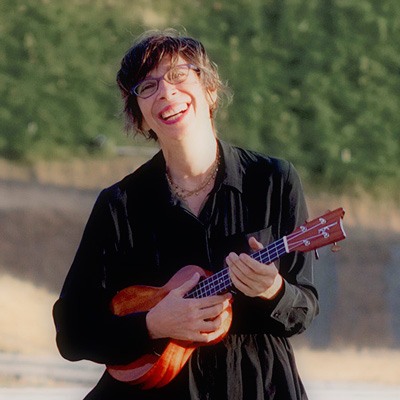 Arni Adler smiling and holding an ukulele.