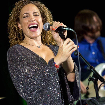 A woman holding a microphone on stage and singing.