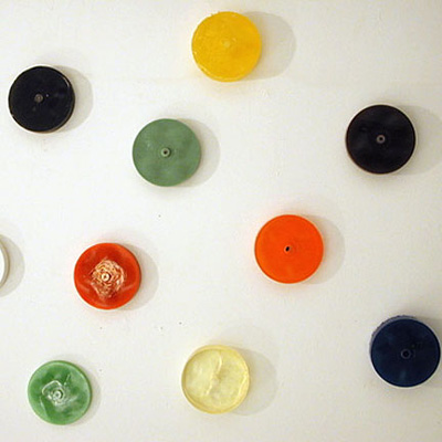 Nine circular shapes of various colors that appear to be mounted on a white wall.