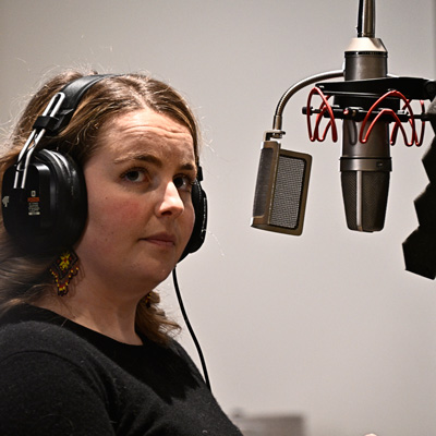 Emily Parzybok, wearing headphones, with a microphone in front of her.