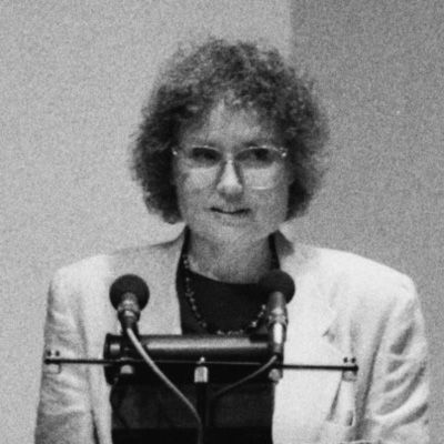 Black and white photo of Diane Westergaard, with two microphones in front of her.