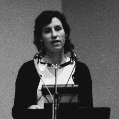 Black and white photo of Lisa Michaels, standing at a lectern.