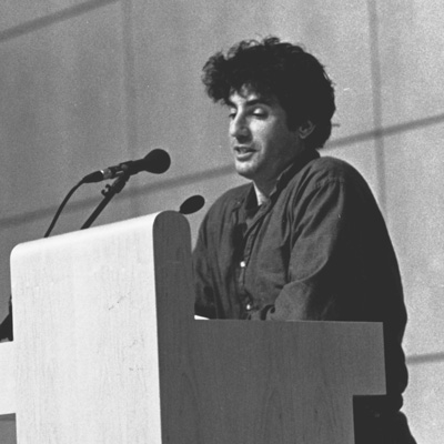 Black and white photo of Daniel Gutierrez, standing at a lectern with a microphone.