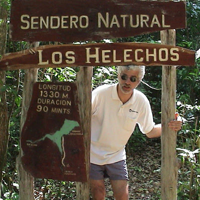 Photo of Andy Schloss posing with a sign that reads "Sendero Natural Los Helechos"