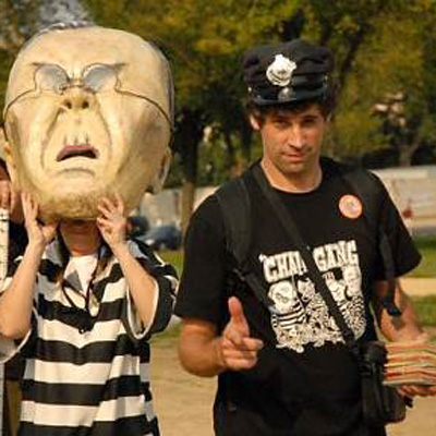 Bill Moyer standing next to someone wearing an oversided puppet head and black and white striped shirt.