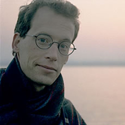 Photo of Bret Battey, with ocean and sky behind him.