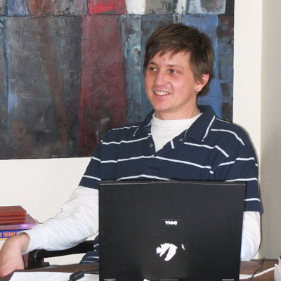 Brian Goedde, seated at a desk with a laptop computer screen in front of him.