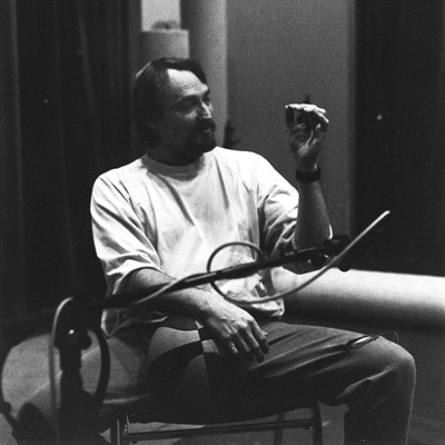 Black and white photo of Gregg Loughridge seated in front of a microphone with a basketball.