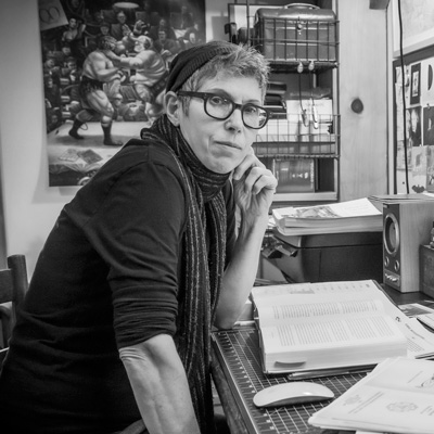 Black and white photo of Nikki Appino, seated, with a book open in front of her