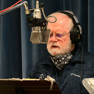 David K. Rea wearing headphones and standing at a microphone.