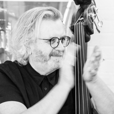 Black and white photo of Michael Bisio applauding while holding an upright bass.