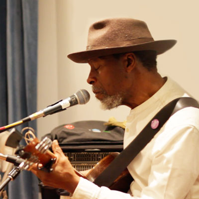 Reggie Garrett playing guitar and singing into a microphone.
