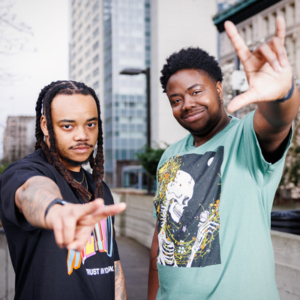 Korbin and Meysha of Transonic, smiling and holding their hands in gestures of peace and love.