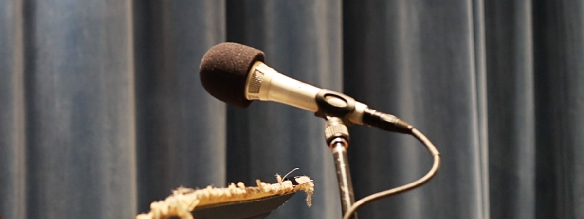 A microphone on a stand with a background of blue-gray curtains