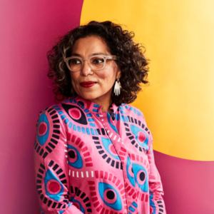 Claudia Castro Luna in front of a pink and yellow background.