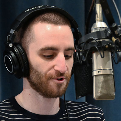 Connor Watkins-Xu, wearing headphones, at a microphone.