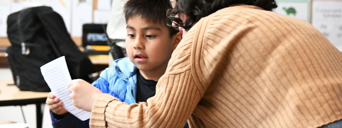 Gabriella and a student holding up a piece of paper and looking at it together.