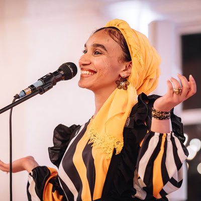 Tasneem stands smiling at a microphone