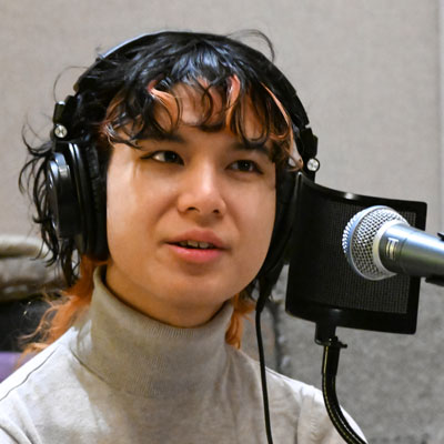 Diane Nguyen at a microphone, wearing headphones.