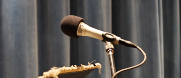 A microphone on a stand with a background of blue-gray curtains