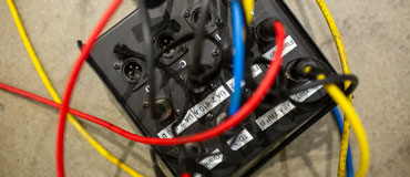 Multi-colored audio cables plugged into a black connection box.